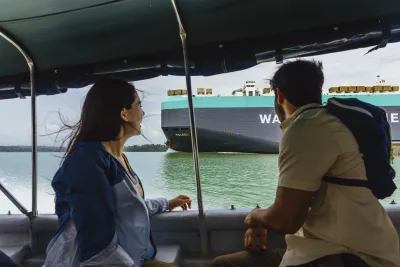 Guests viewing a ship from a boat on the Panama Canal